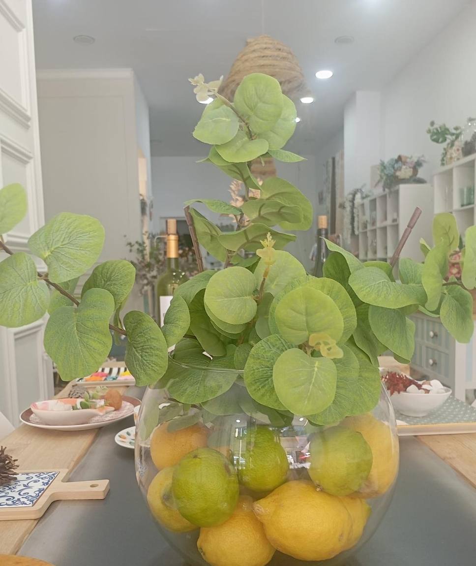 Jarrón de cristal con limones dentro y eucalipto asomando por arriba