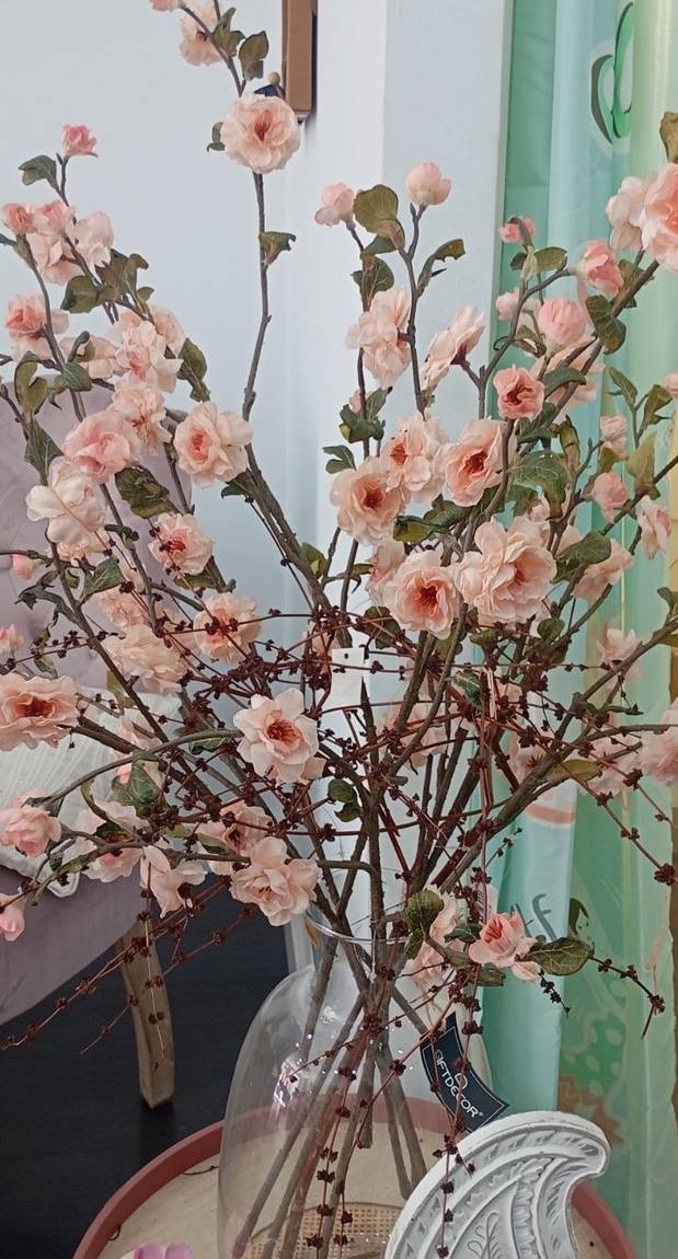 Rama alta de flor de melocotón en un jarrón para un recibidor de techo alto