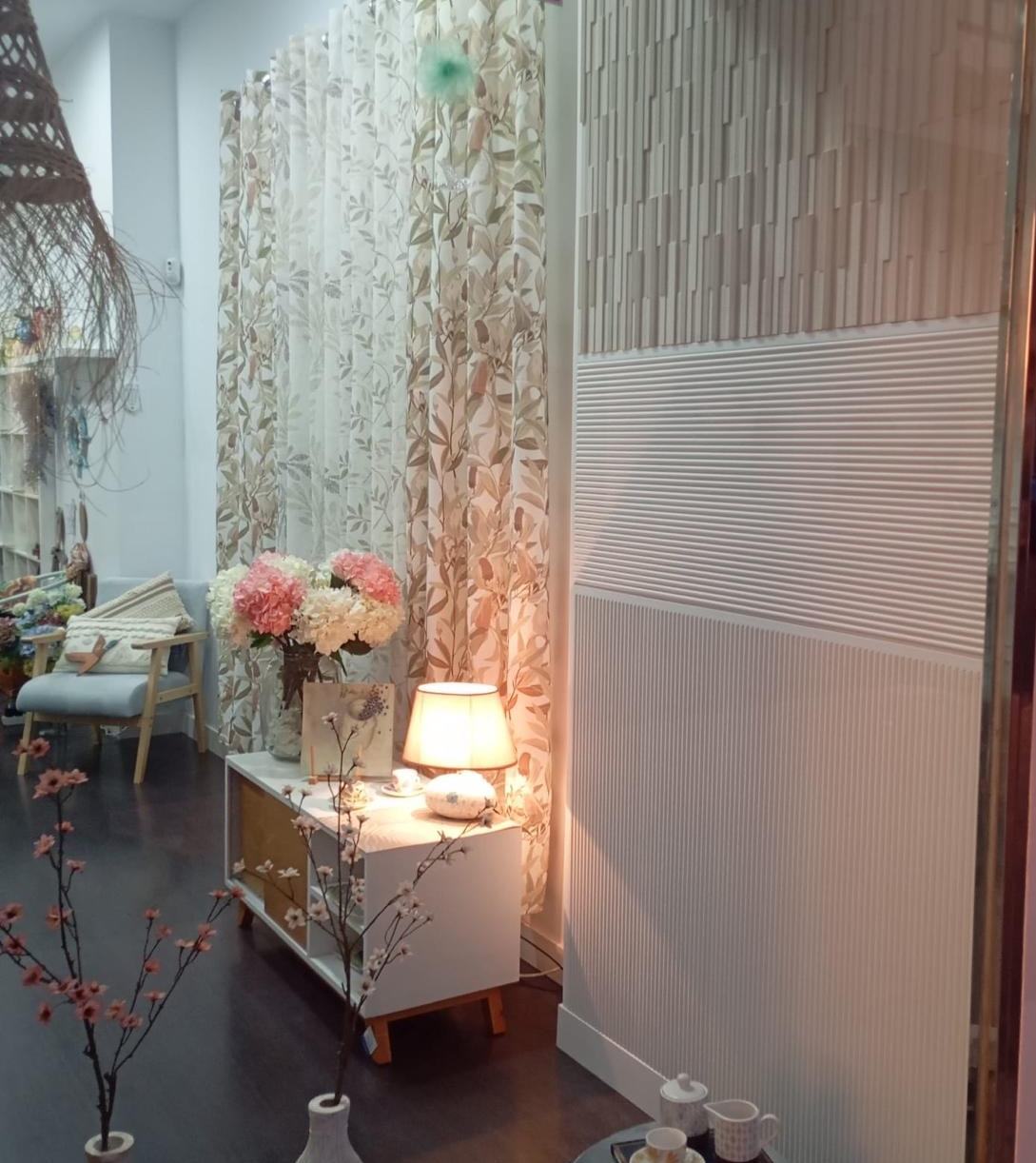 Rincón de la tienda Quitita Home con panel ranurado, consola y flores